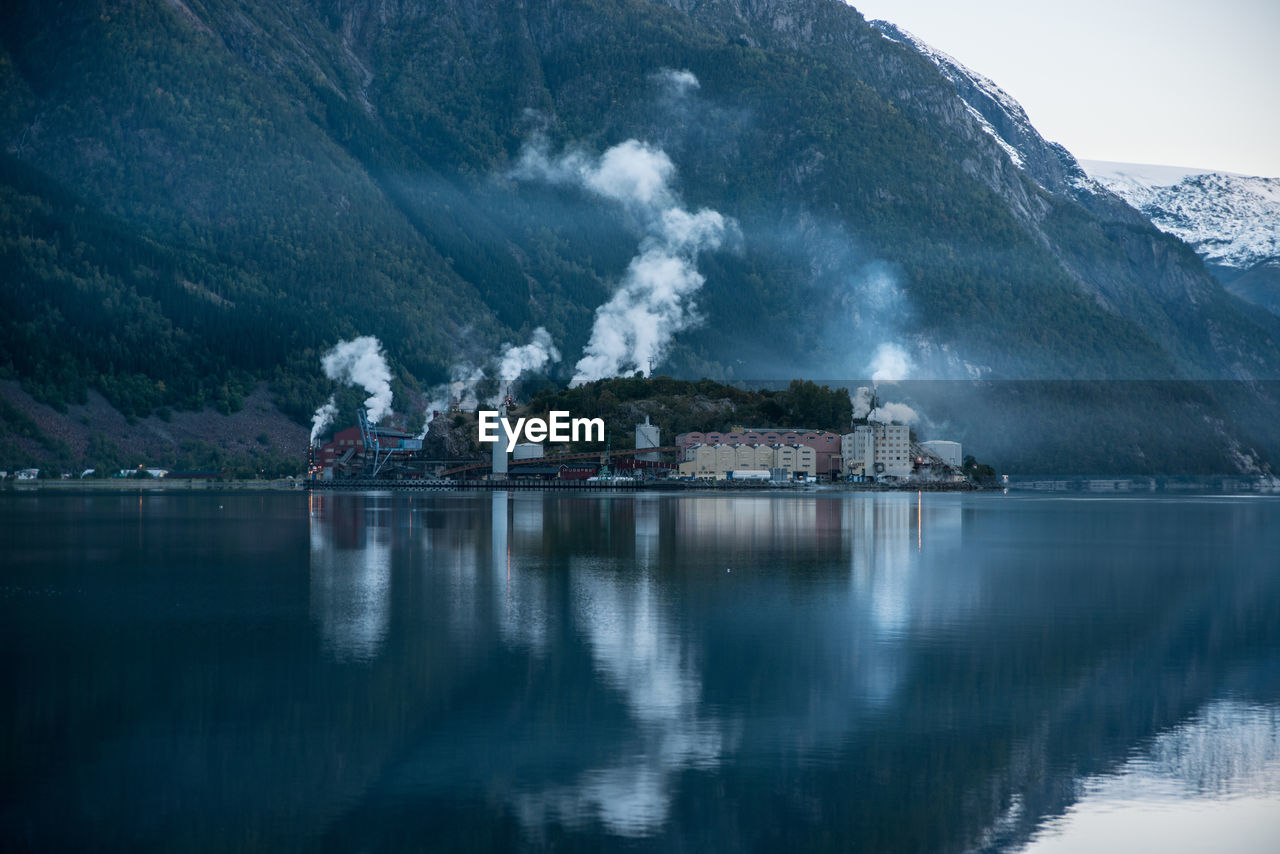 Factory by lake and mountain