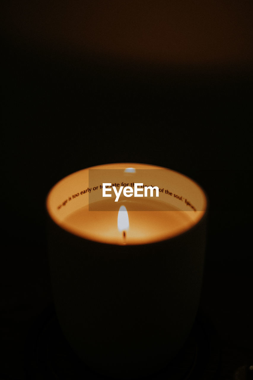 CLOSE-UP OF LIT CANDLE IN DARK