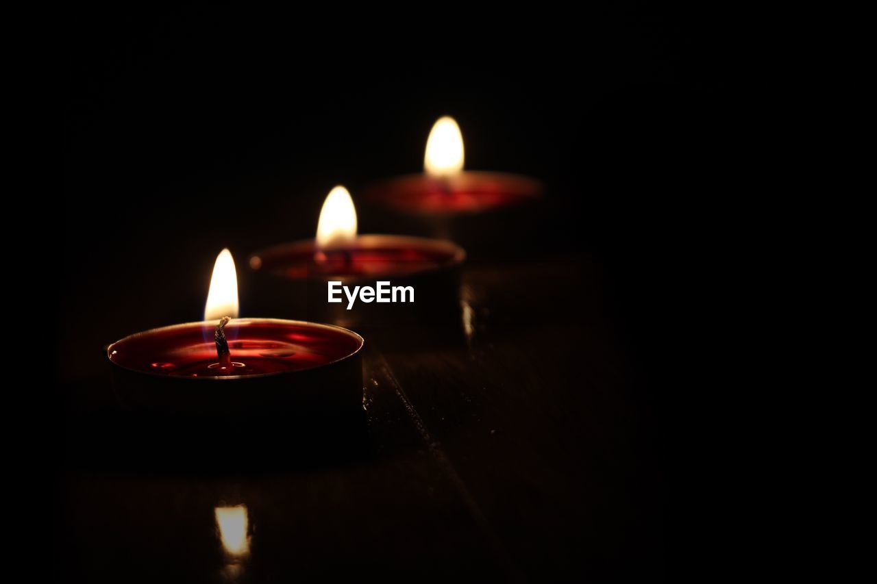 Close-up of illuminated candles in darkroom