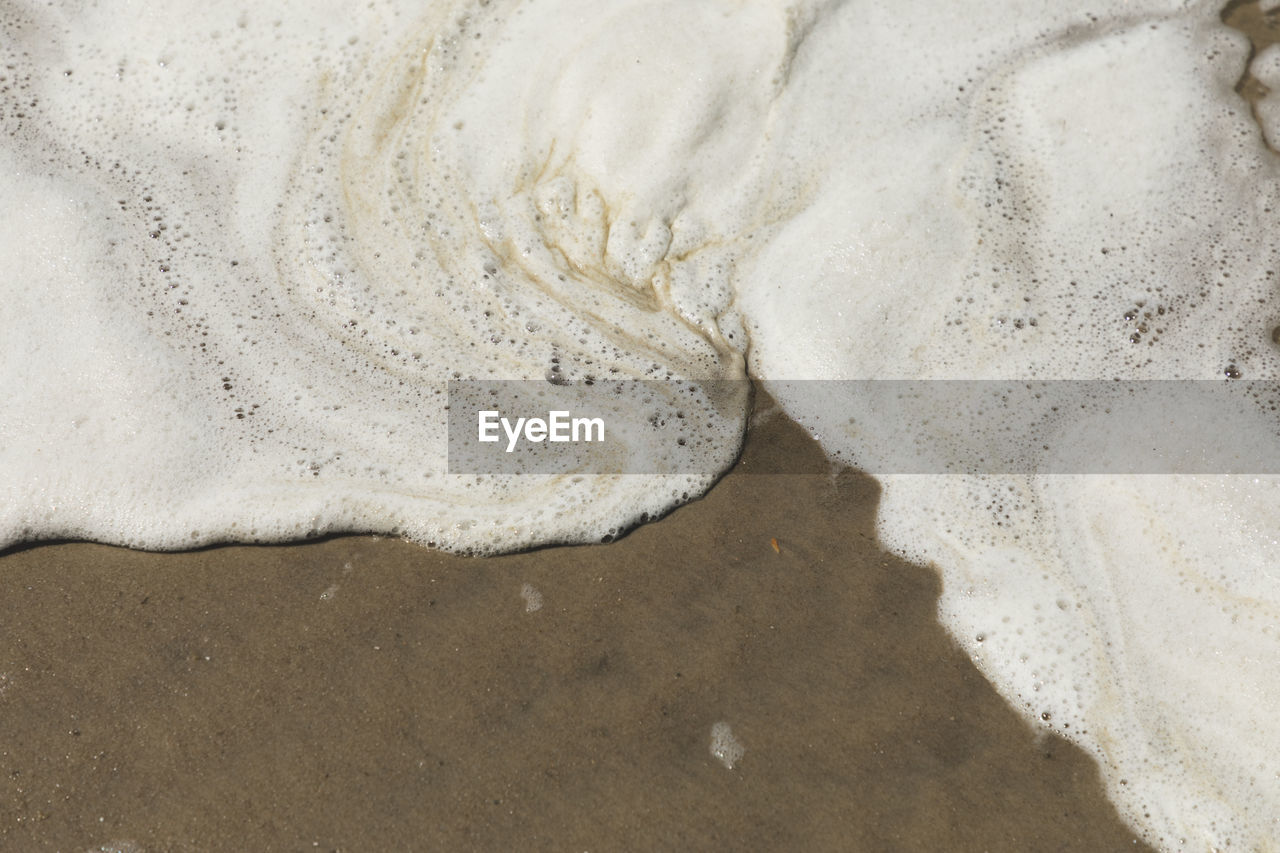 CLOSE-UP OF BUBBLES ON SANDY BEACH