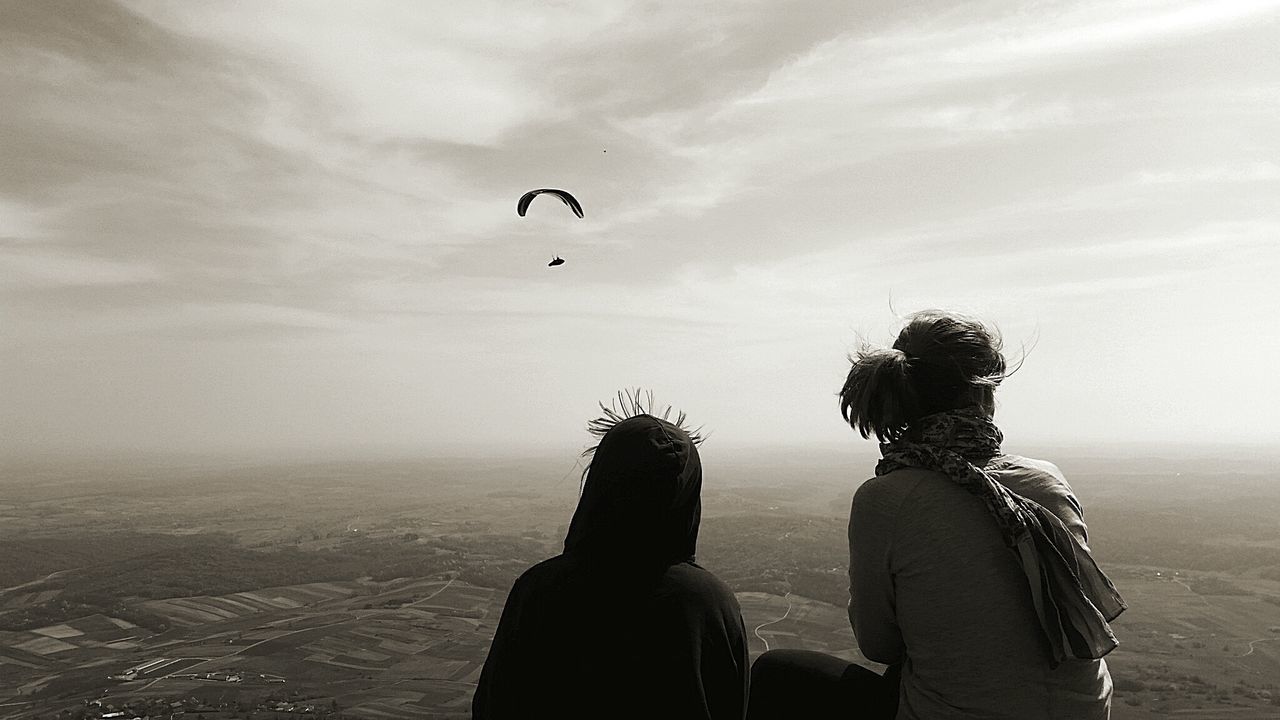 REAR VIEW OF SILHOUETTE MEN FLYING OVER SEA