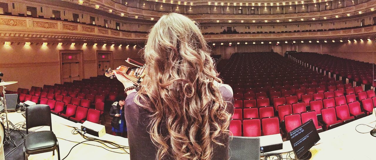 rear view, indoors, stage theater, real people, architecture, auditorium, long hair, sitting, one person, standing, blond hair, seat, illuminated, day, people