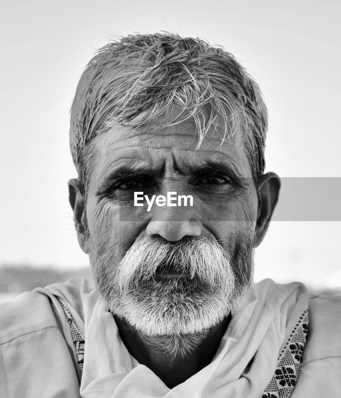 Close-up portrait of senior man with beard against clear sky