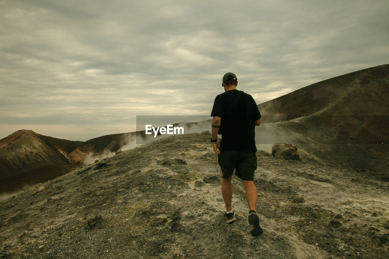 FULL LENGTH REAR VIEW OF MAN STANDING ON MOUNTAIN