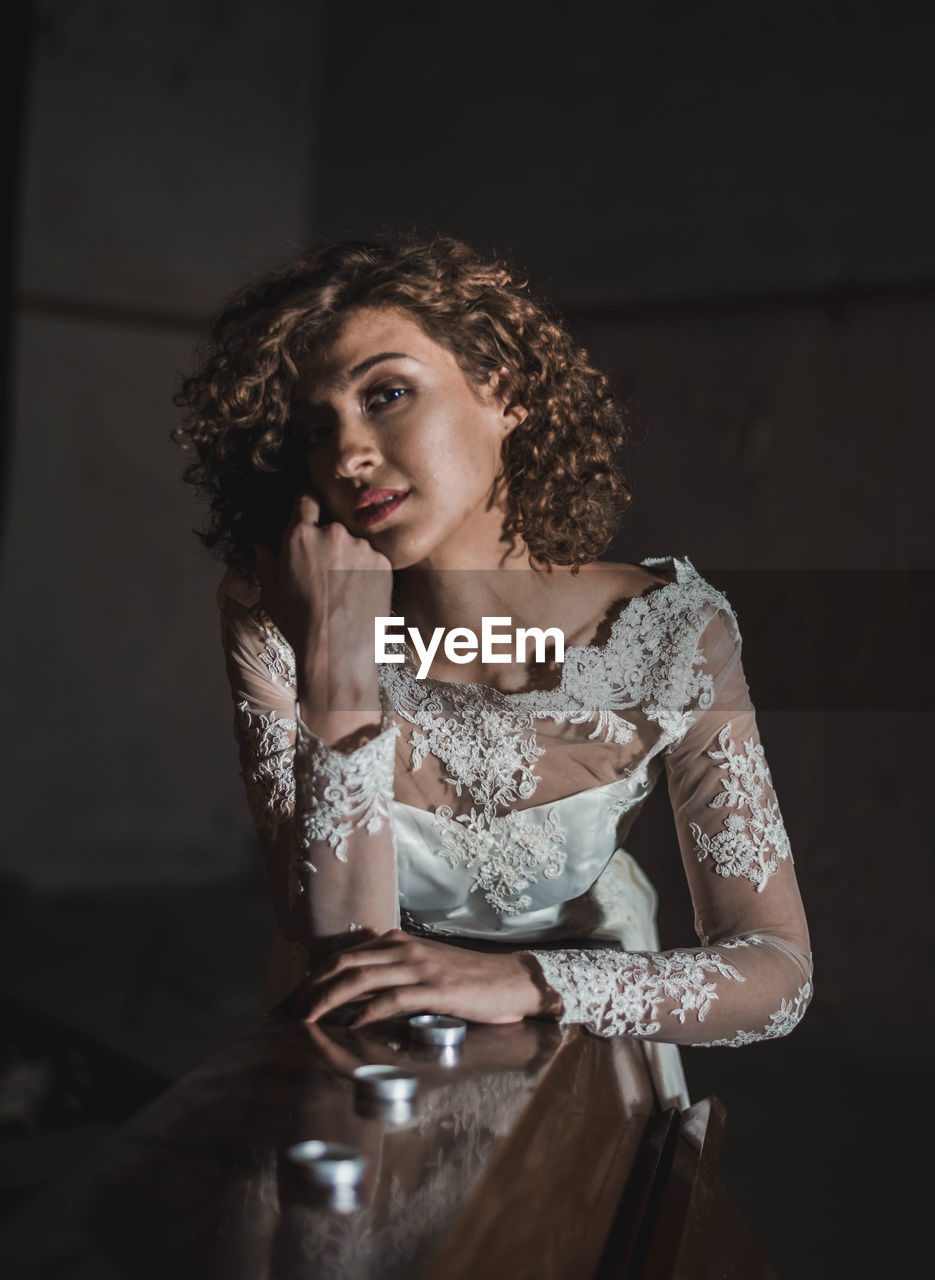 Portrait of beautiful woman in wedding dress leaning on piano at home