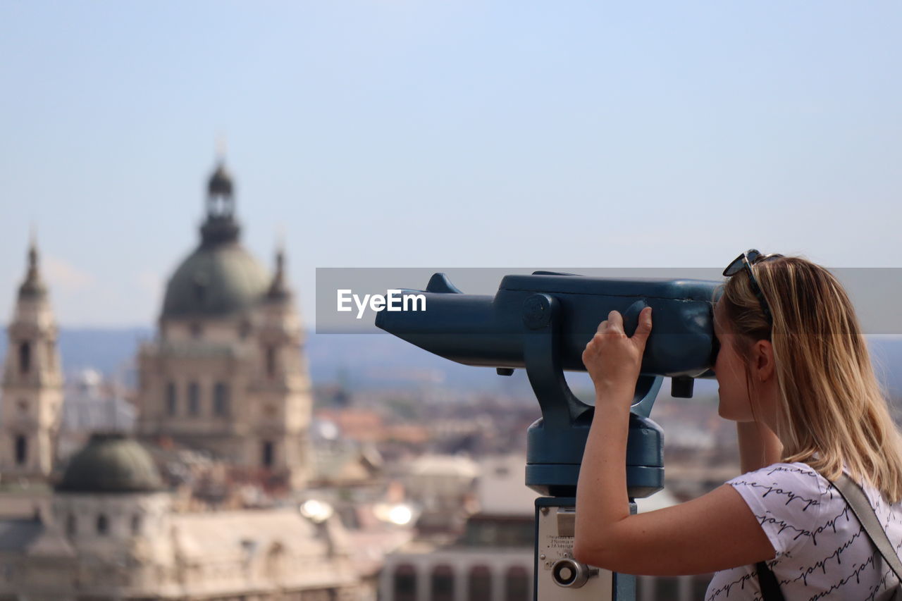 Woman using binoculars against sky