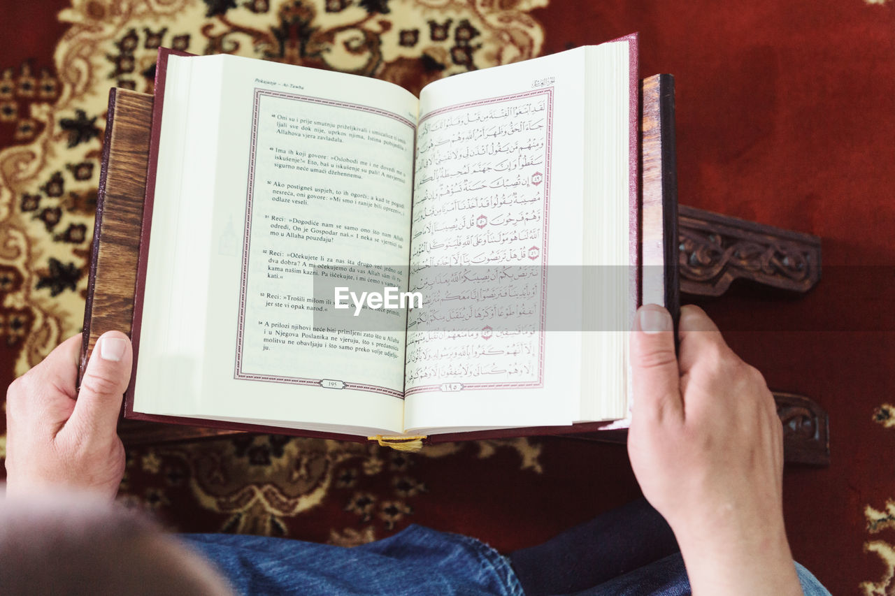 Midsection of man reading koran in mosque