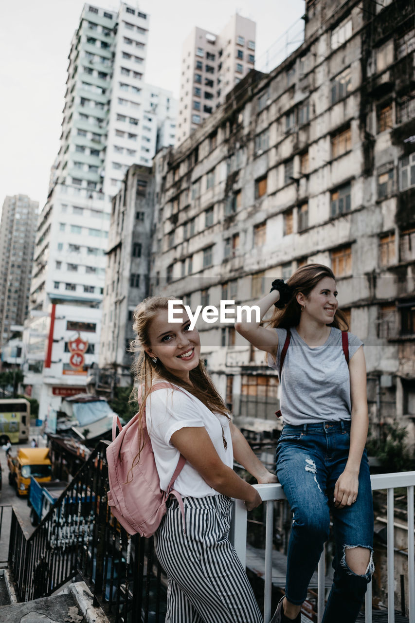 Smiling friends against buildings in city