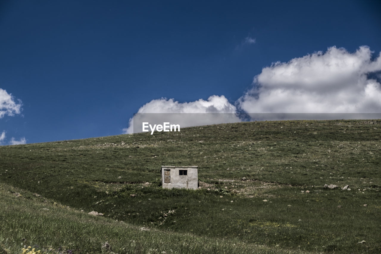 BUILDING ON FIELD AGAINST SKY