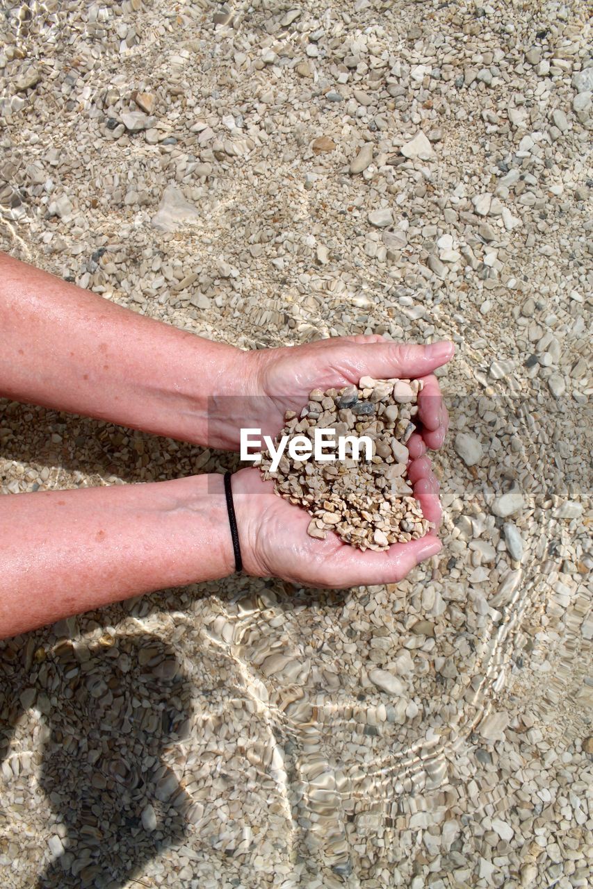 Close-up of hand holding stones on beach