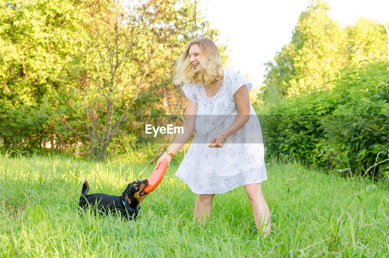 Smiling young woman playing with dog on grass