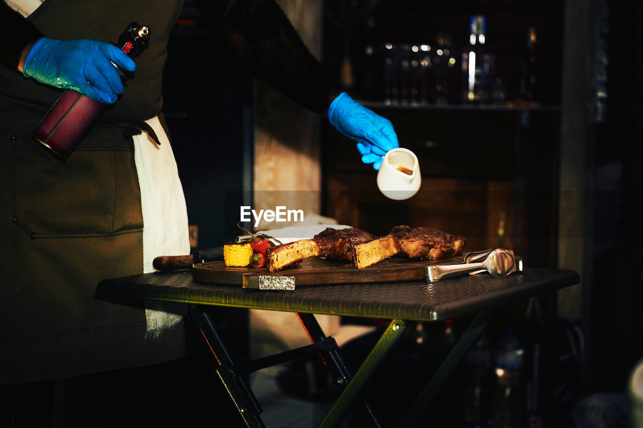 cropped hand of person preparing food on barbecue grill