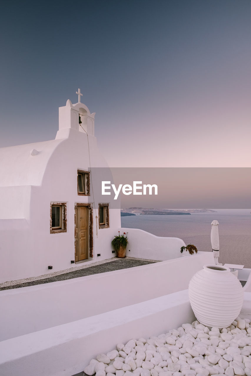 BUILDING BY SEA AGAINST SKY DURING SUNSET