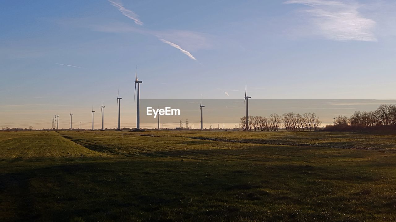 WIND TURBINES IN FIELD AGAINST SKY