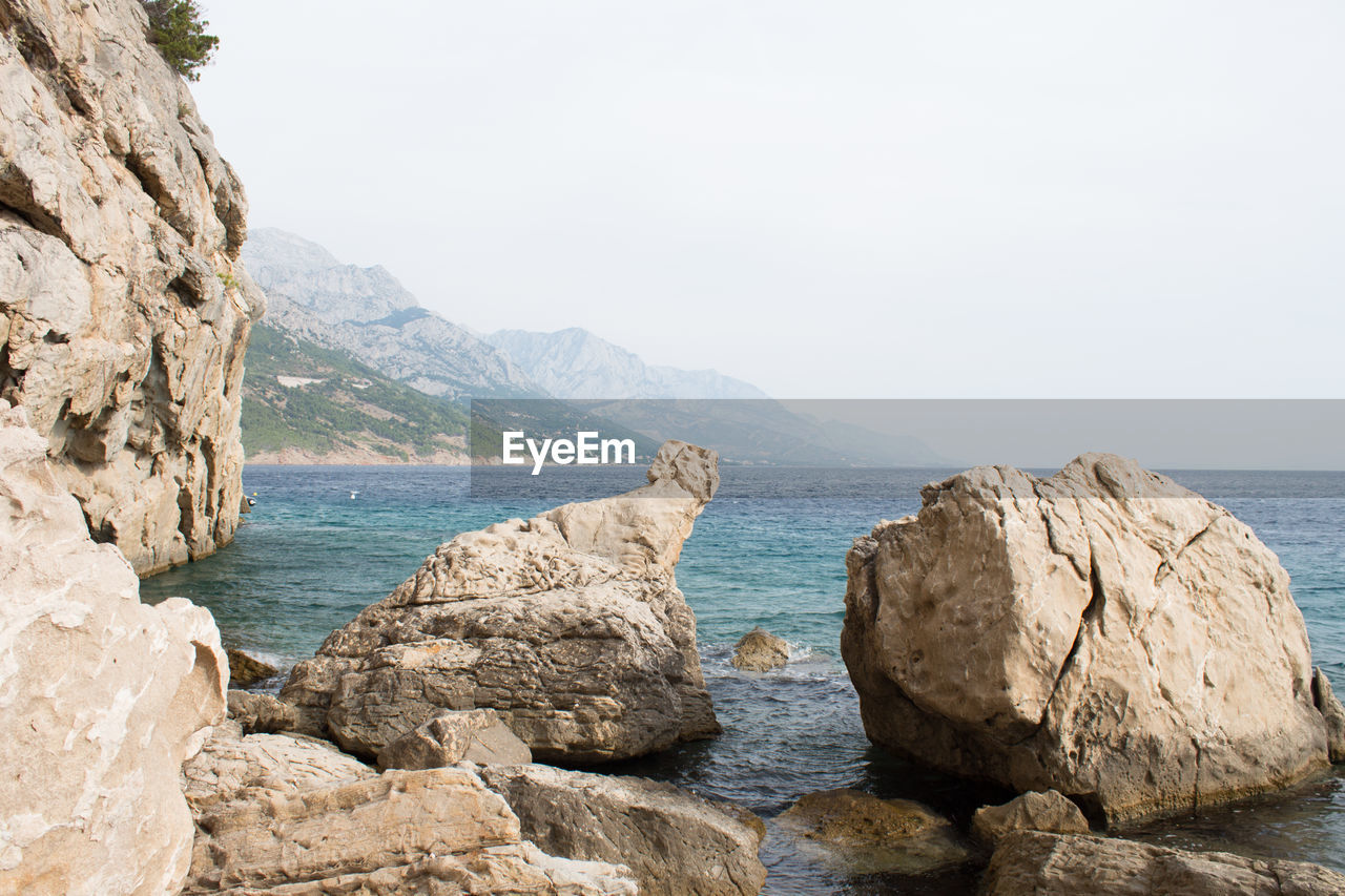 Rocks in sea against clear sky