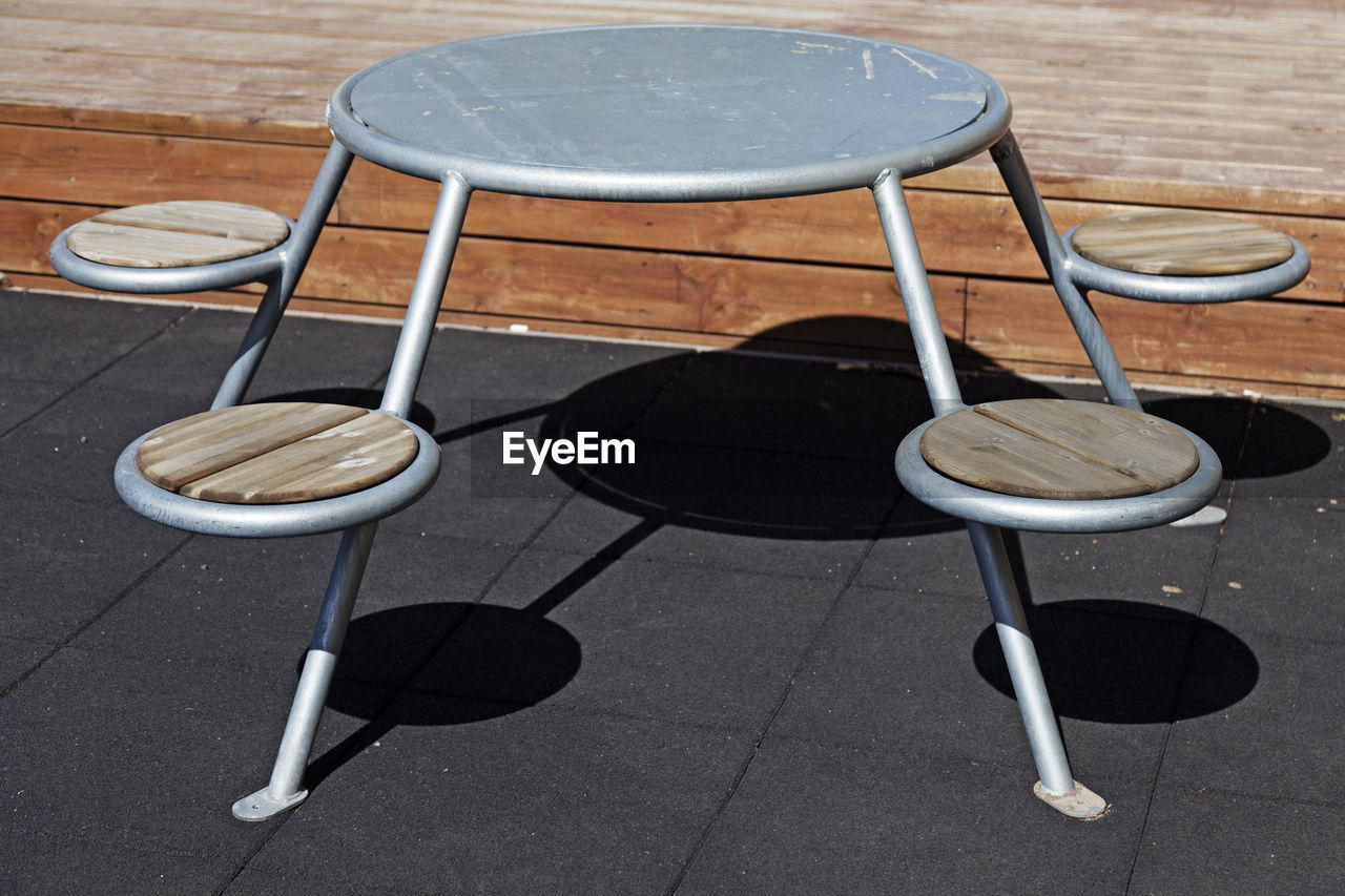 HIGH ANGLE VIEW OF EMPTY CHAIRS AND TABLE ON FOOTPATH