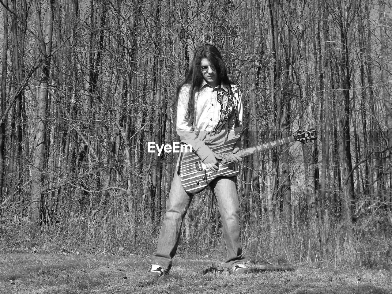 Woman playing guitar against trees