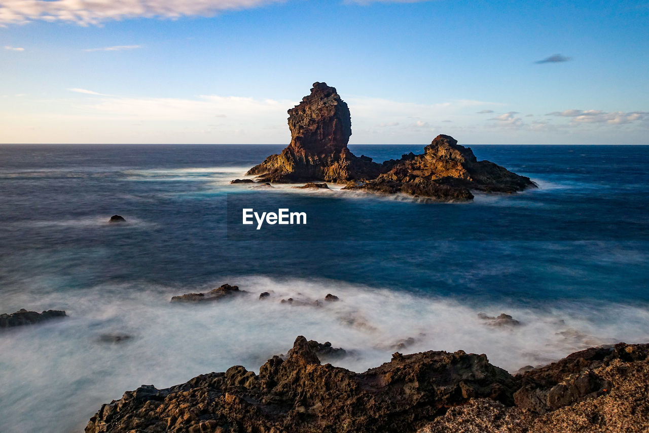 Scenic view of rocks on beach against sky