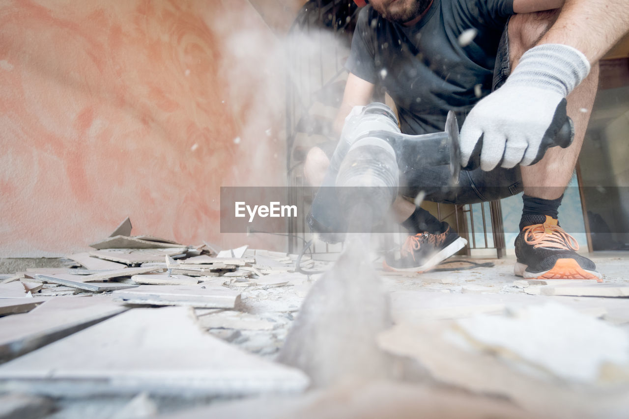 MIDSECTION OF MAN WORKING ON METAL IN KITCHEN