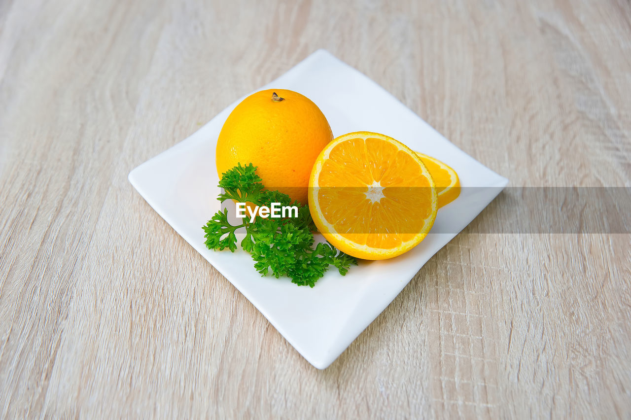 High angle view of oranges in plate on wooden table
