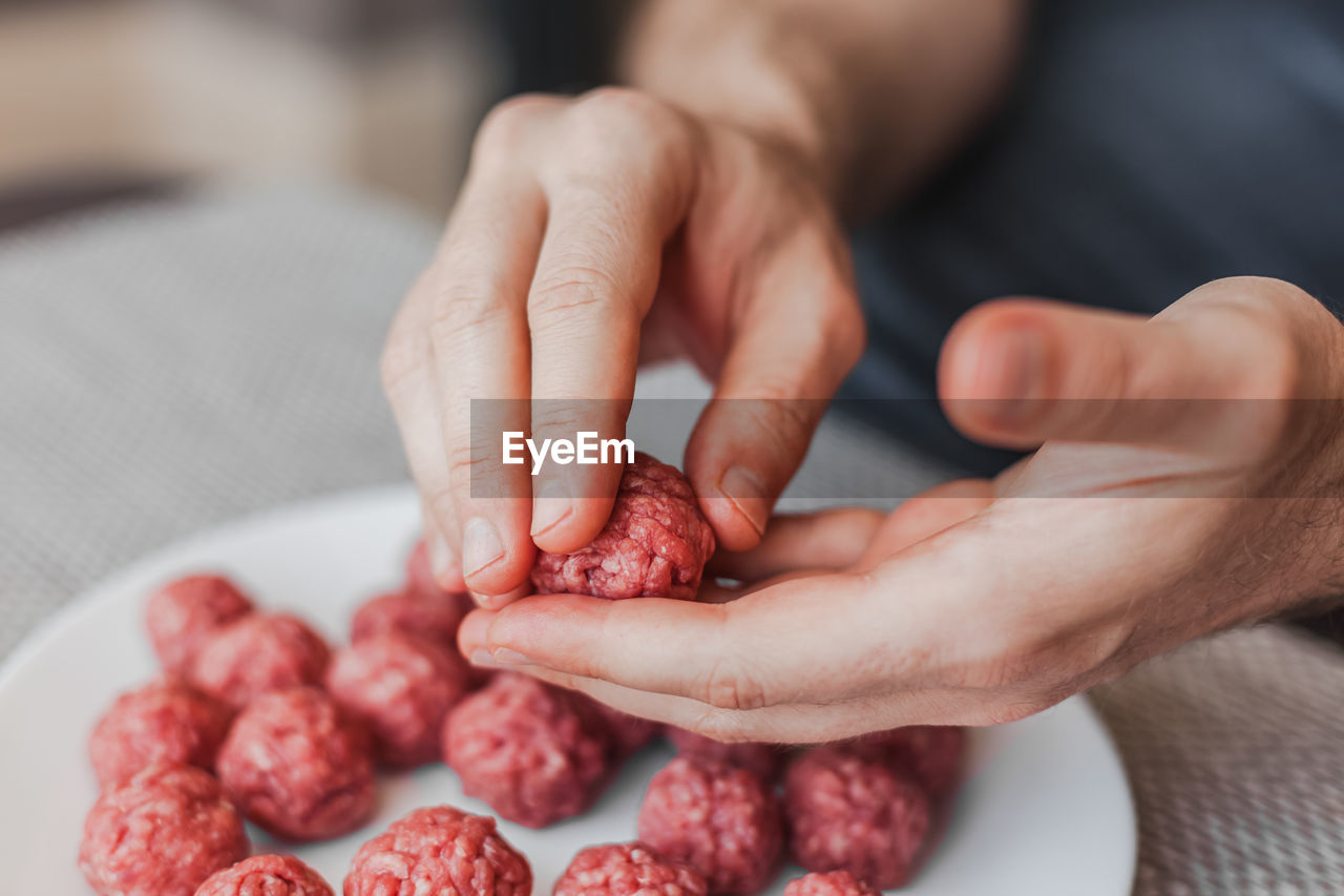 CROPPED IMAGE OF MAN PREPARING MEAT