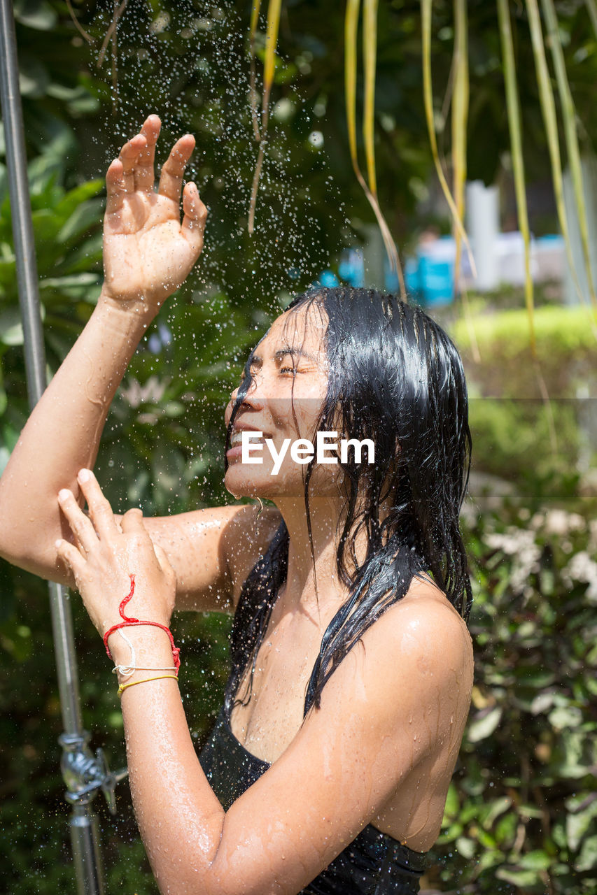 Woman taking outdoor shower against plants