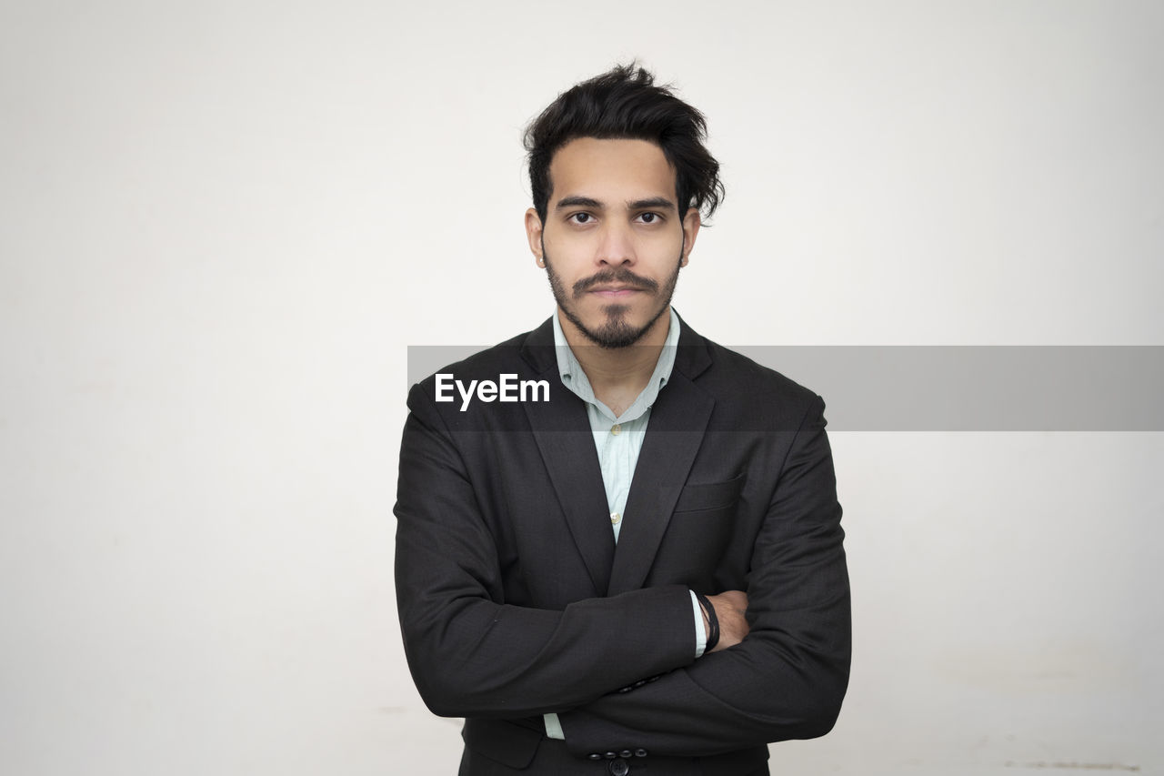 PORTRAIT OF YOUNG MAN STANDING AGAINST WALL