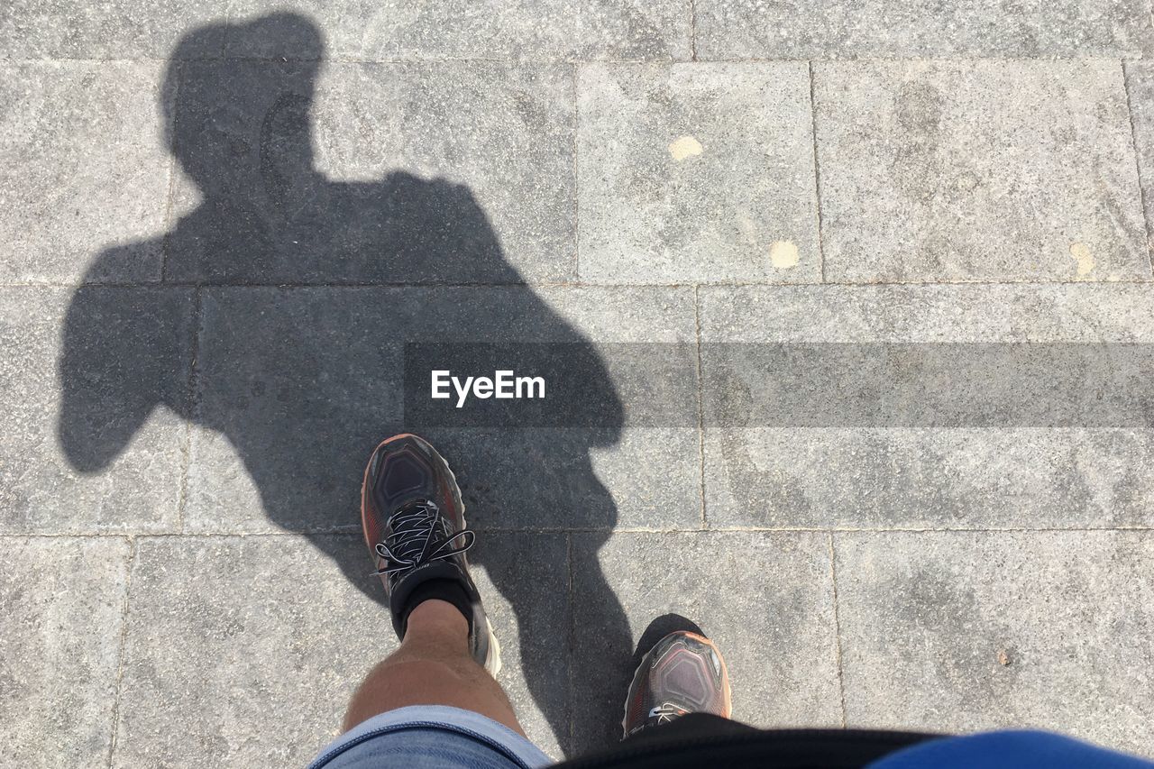 LOW SECTION OF MAN STANDING ON SHADOW