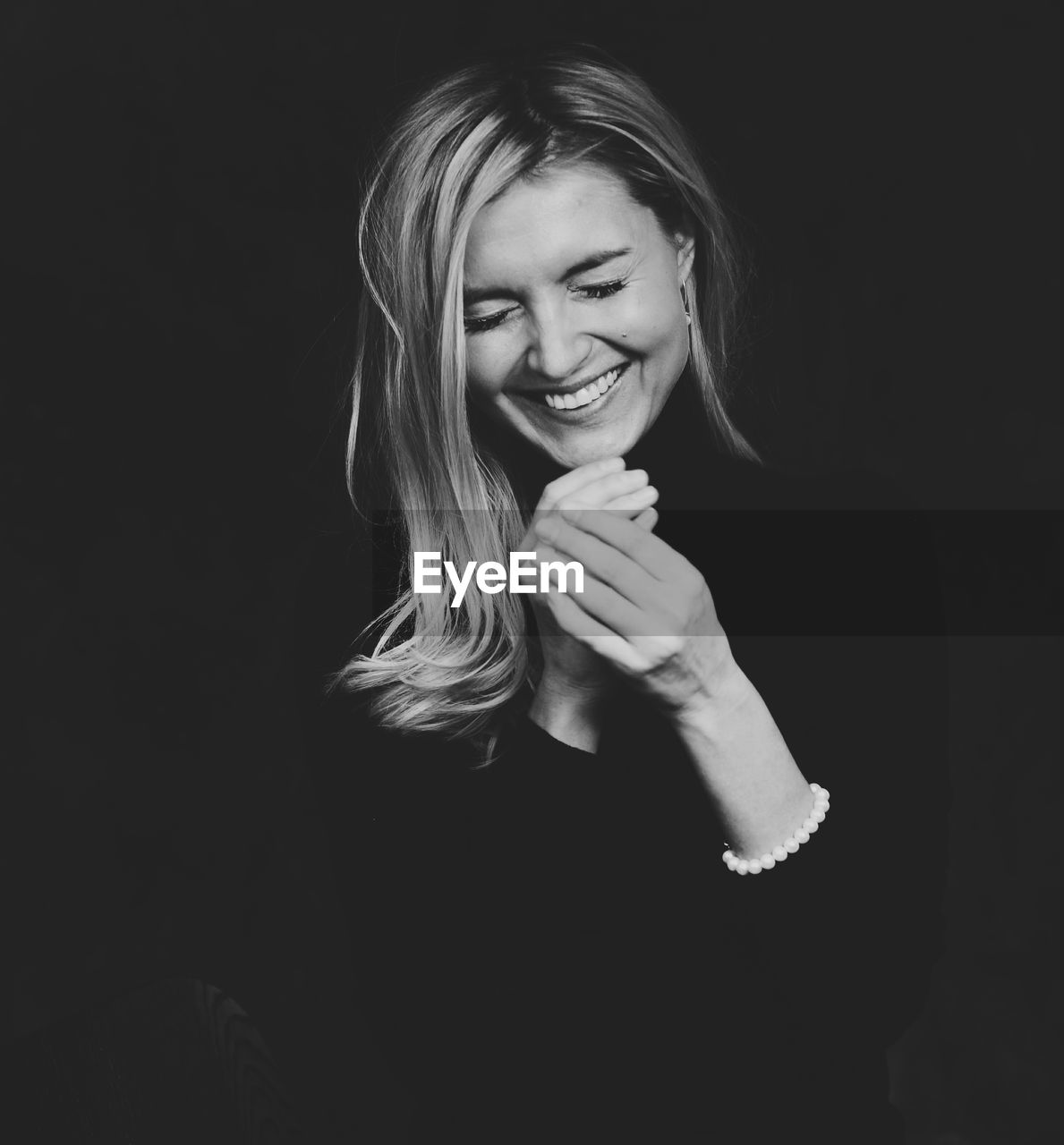 Portrait of smiling young woman against black background