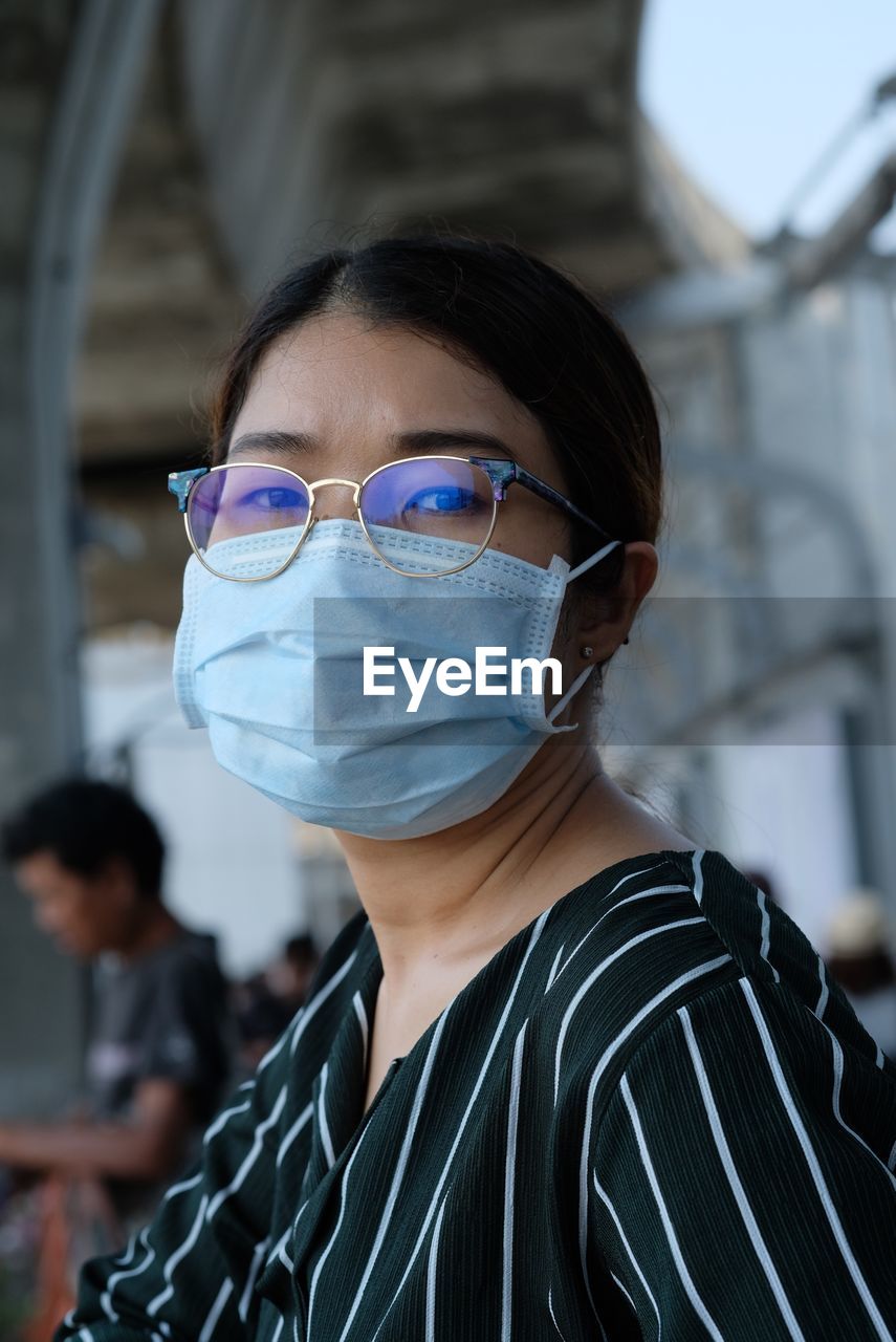 Portrait of woman wearing eyeglasses and flu mask at airport