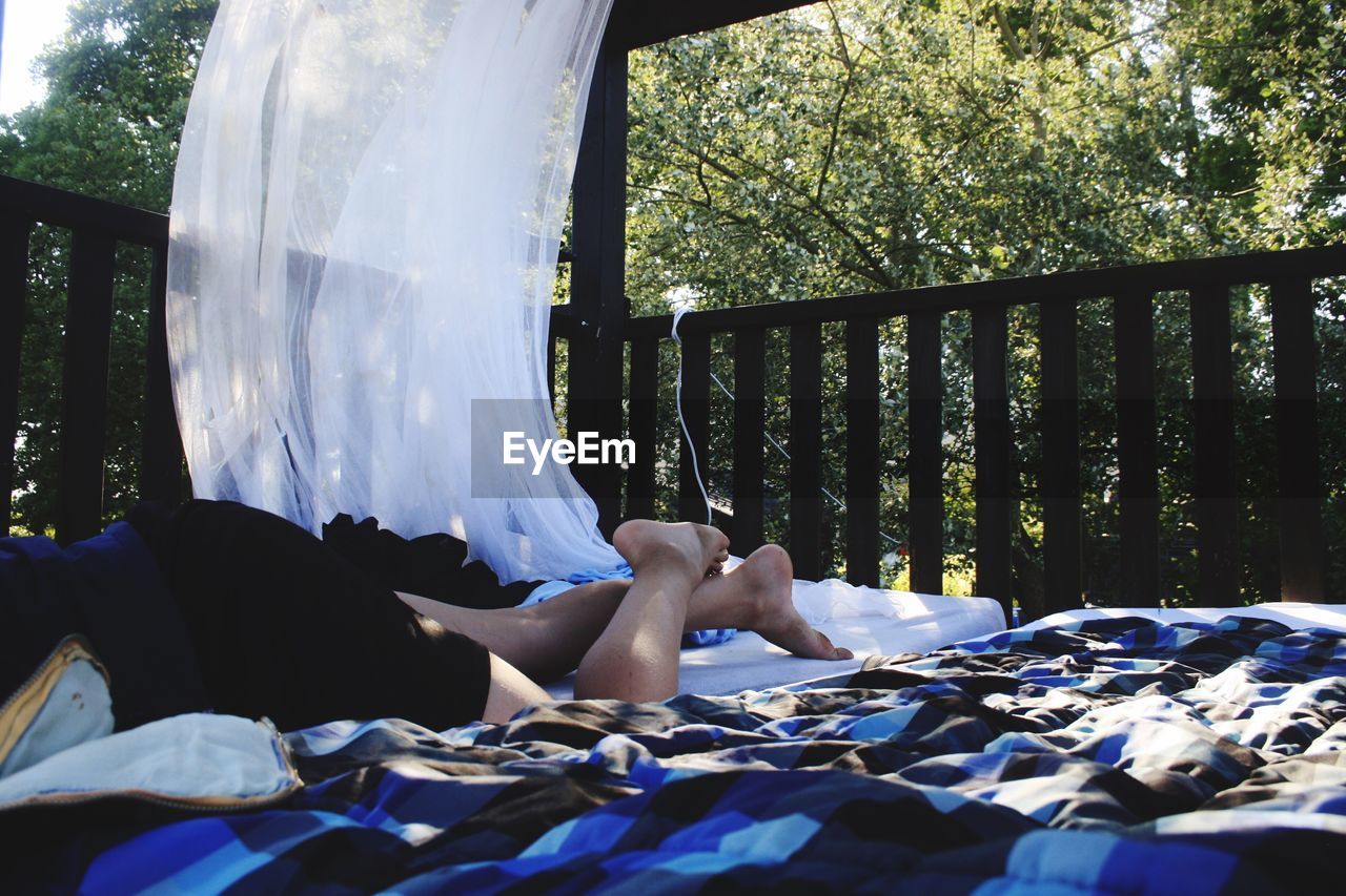 Low section of man lying on bed in balcony