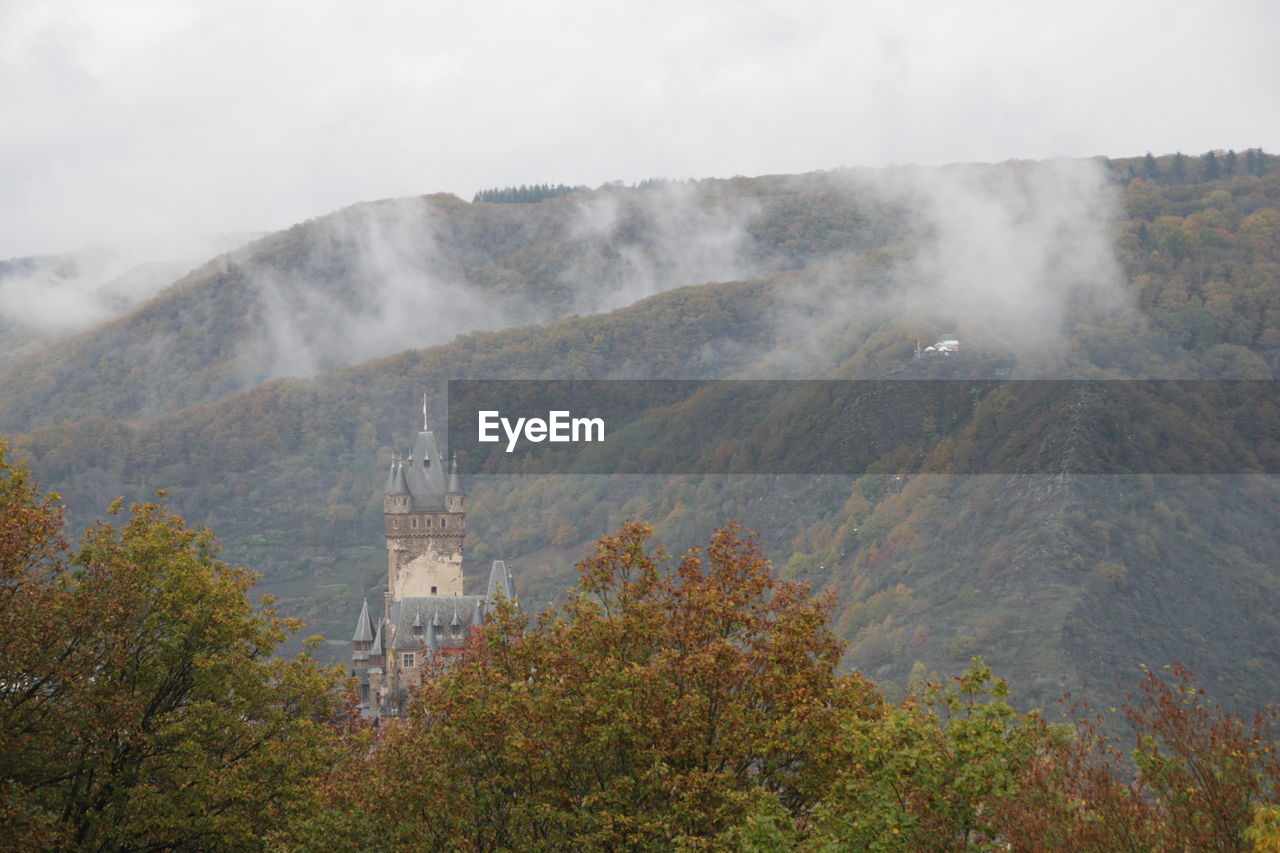 Scenic view of trees and castel uring foggy weather