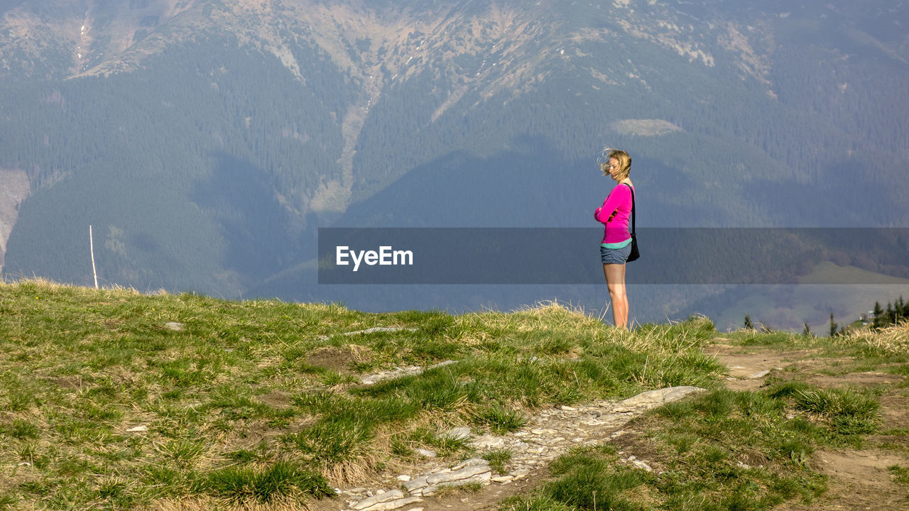 Side view of woman standing on land against mountain