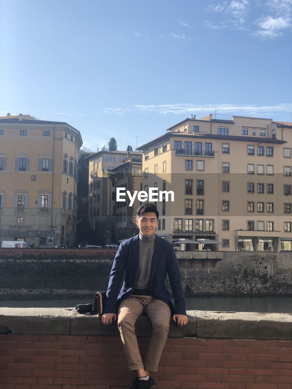 Portrait of young man sitting against building