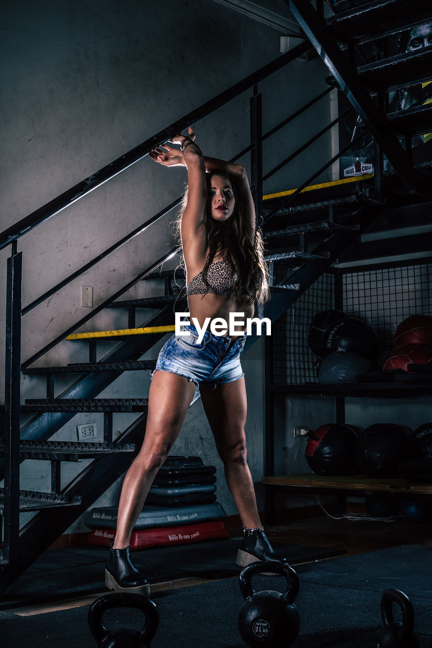 Full length of woman with arms raised standing in gym