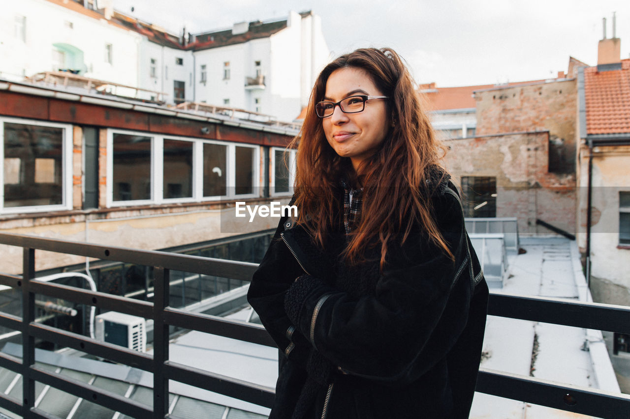 Thoughtful young woman looking away while standing by railing