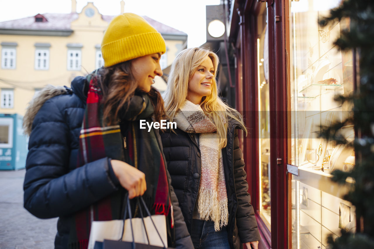 Friends looking through window of store at christmas market