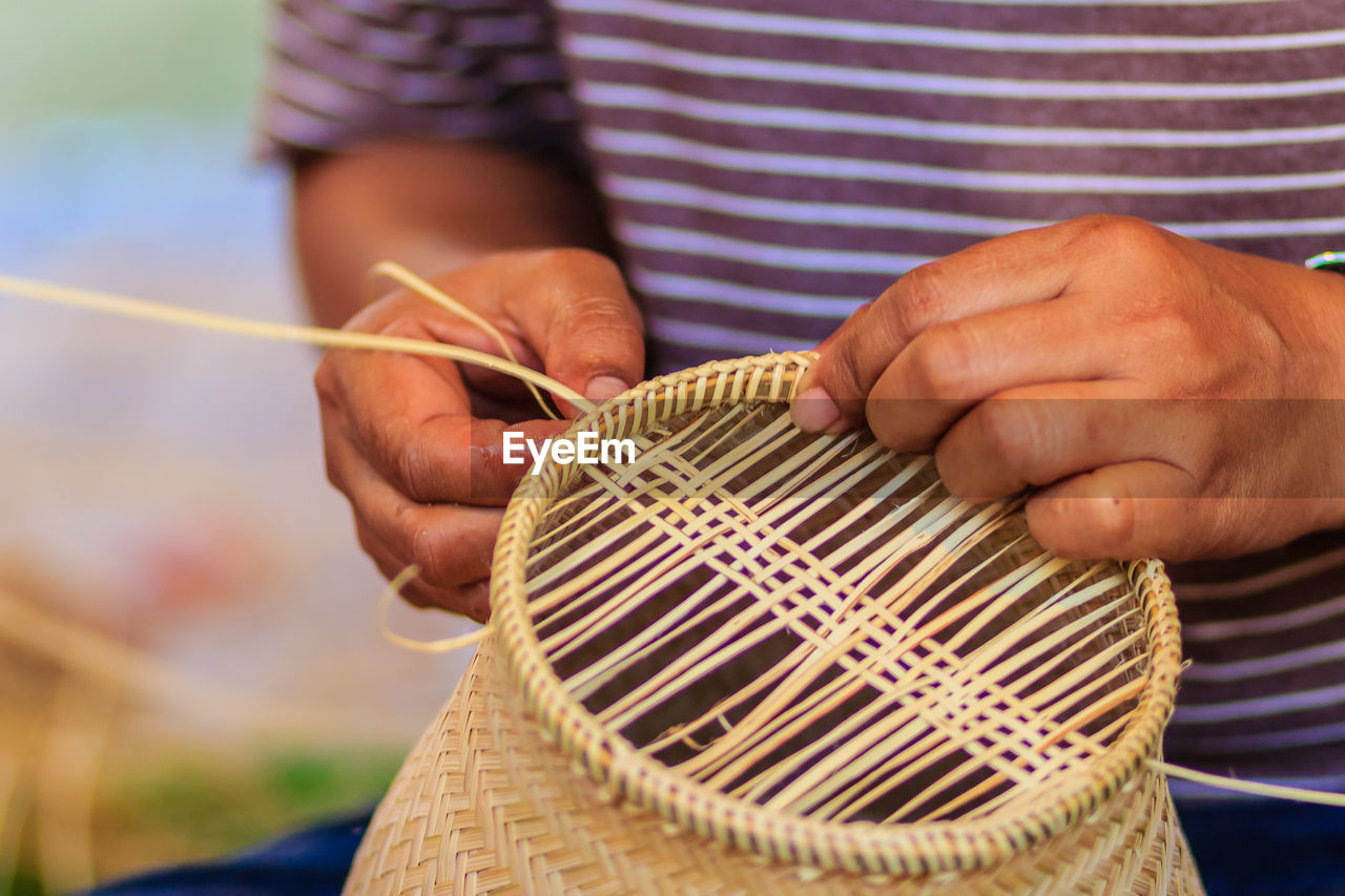 Midsection of man making wicker decoration