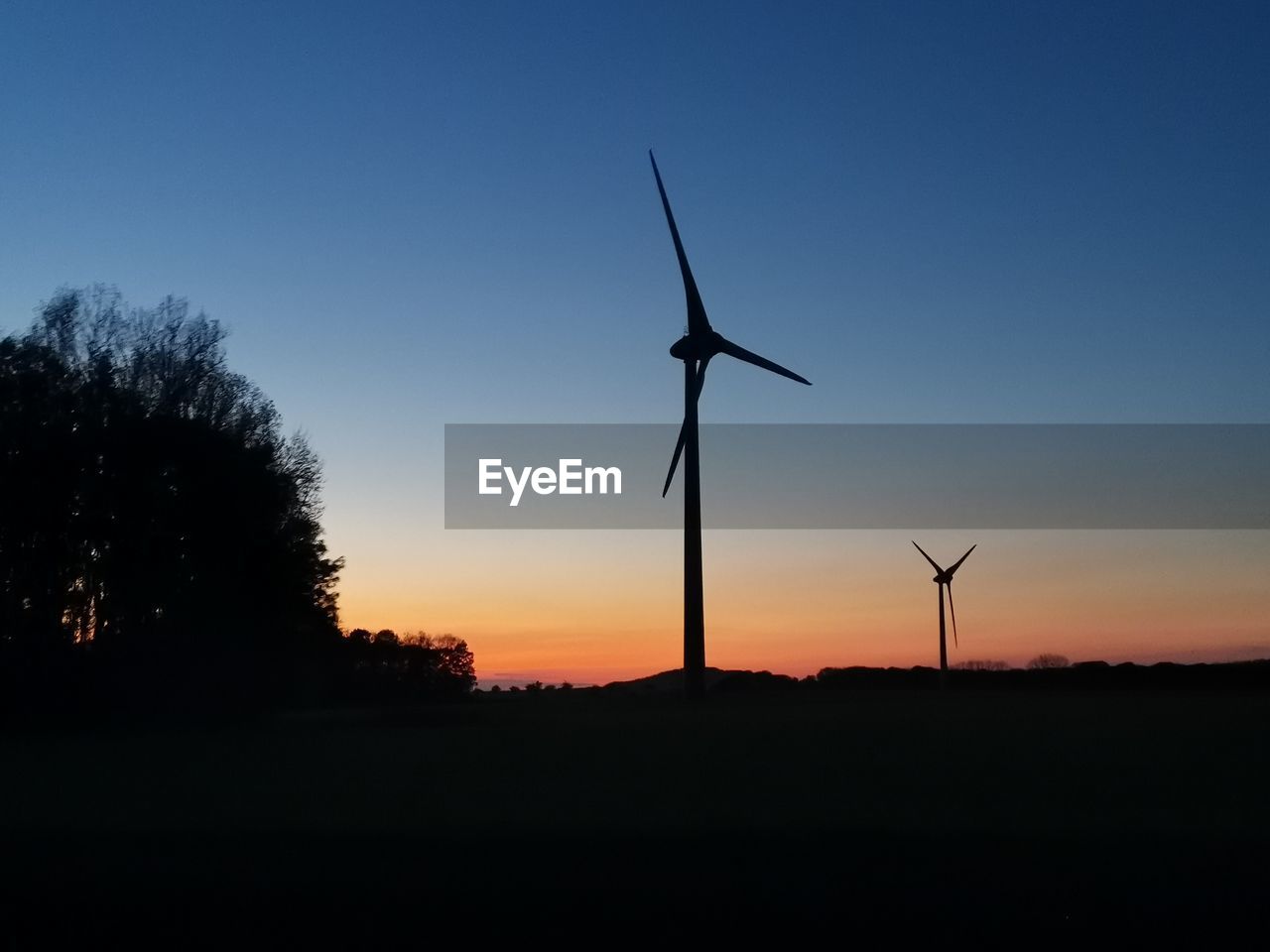 SILHOUETTE WINDMILL ON FIELD AGAINST SKY AT SUNSET