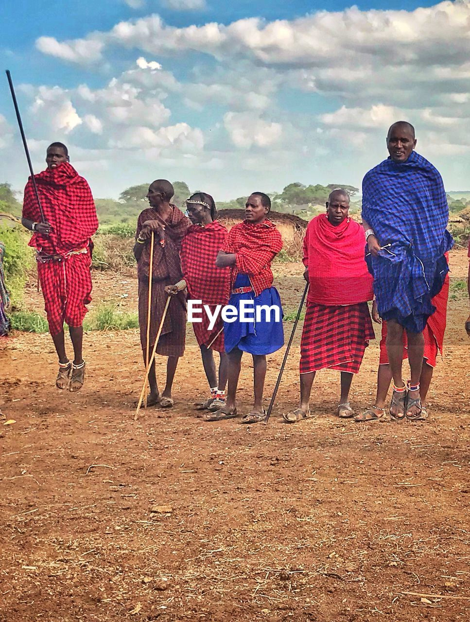 REAR VIEW OF PEOPLE STANDING ON ROAD