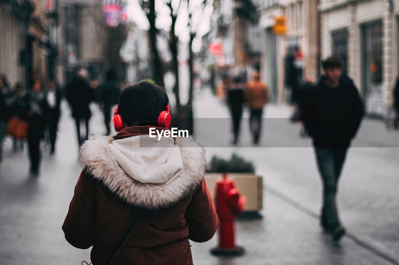 Rear view of woman walking on street during winter