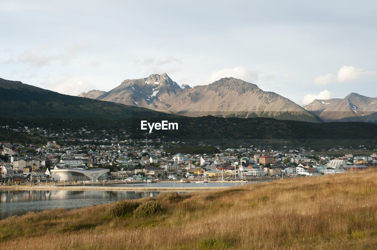 Scenic view of townscape by mountains against sky