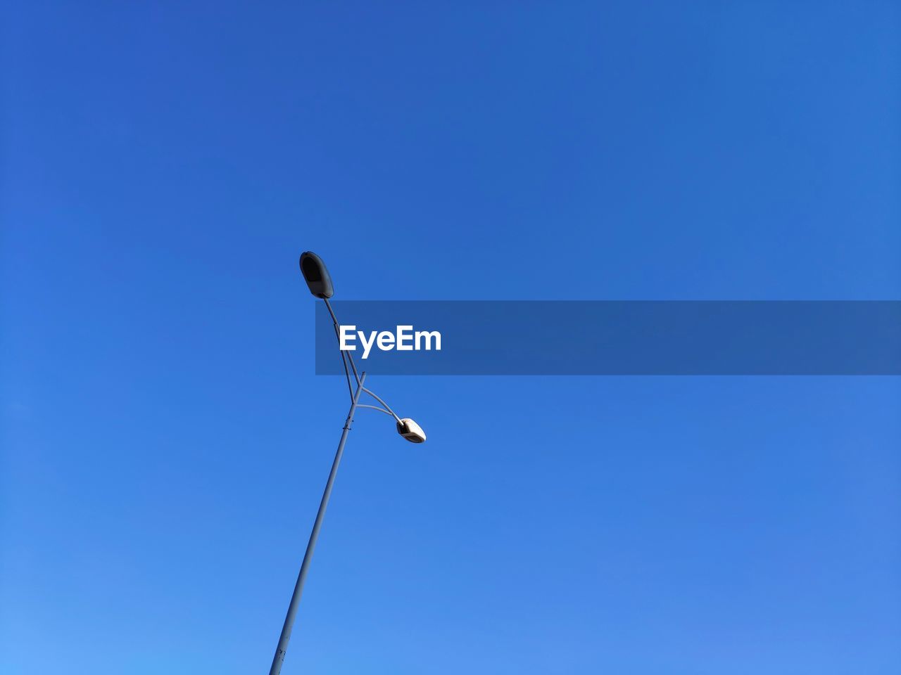 LOW ANGLE VIEW OF STREET LIGHTS AGAINST CLEAR BLUE SKY