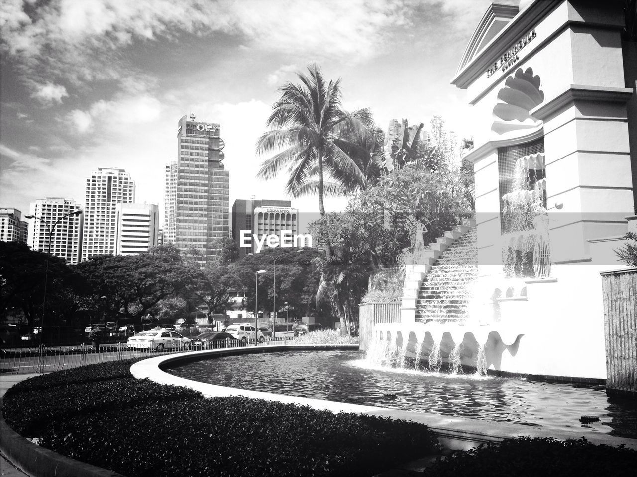 Fountain by building in city against sky