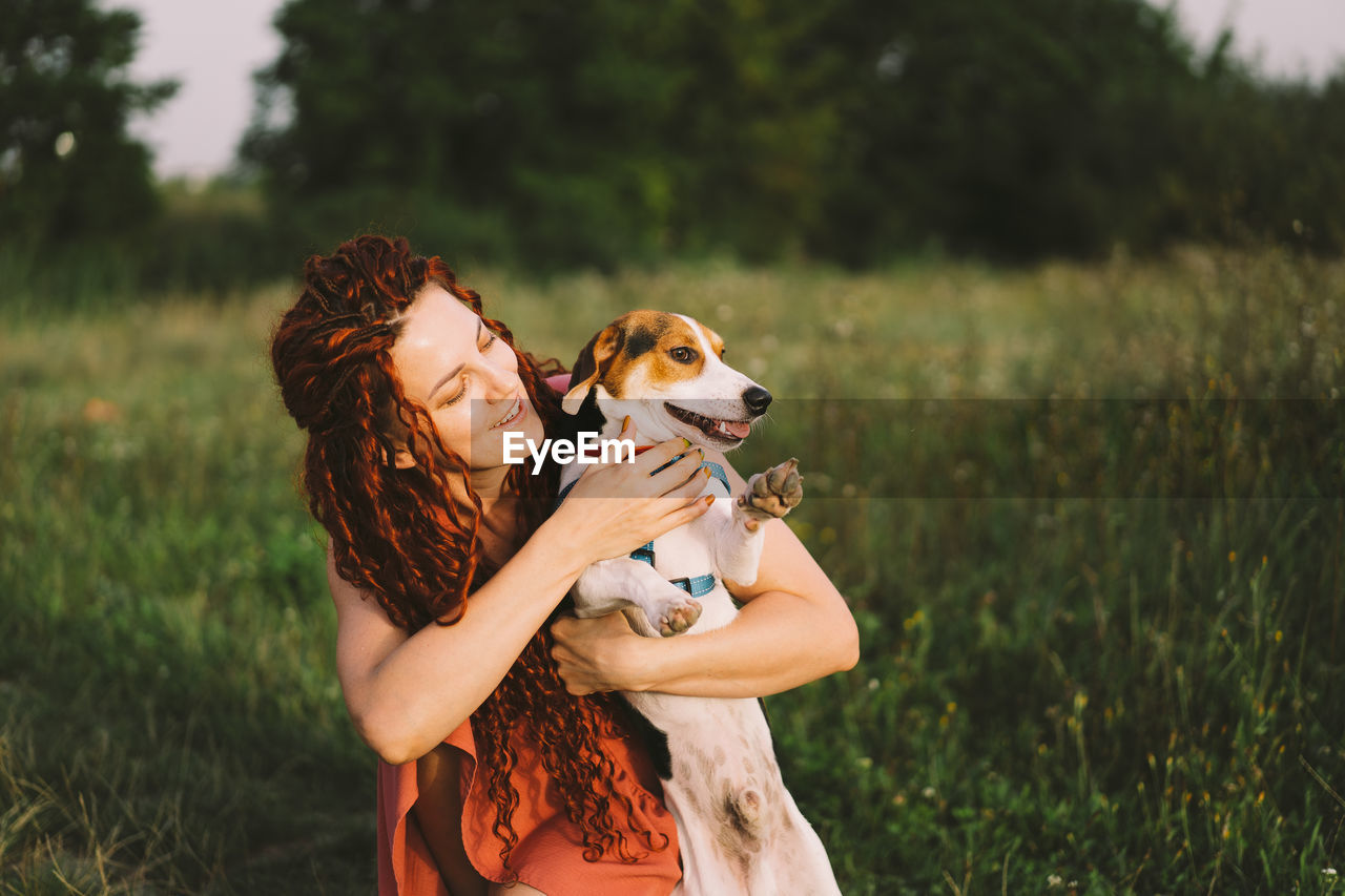 Beautiful woman plays with her jack russell dog in the park.