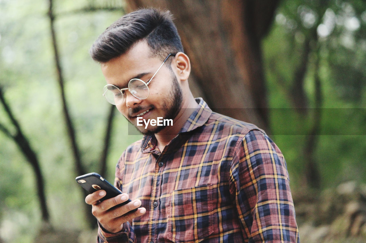 PORTRAIT OF YOUNG MAN USING SMART PHONE