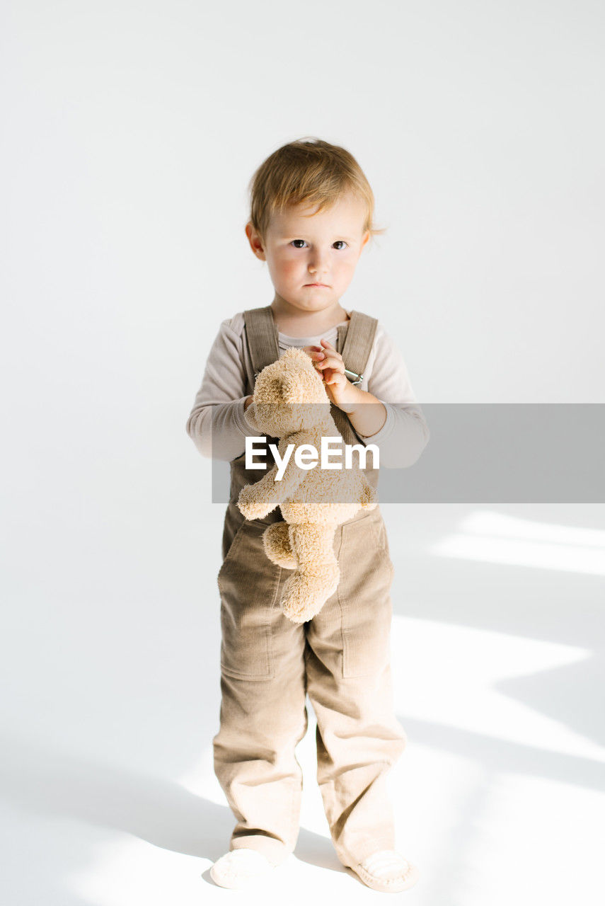 childhood, child, one person, full length, baby, toddler, portrait, studio shot, indoors, men, standing, cute, white background, looking at camera, innocence, front view, toy, sitting, spring, person, emotion, holding, clothing, casual clothing, smiling