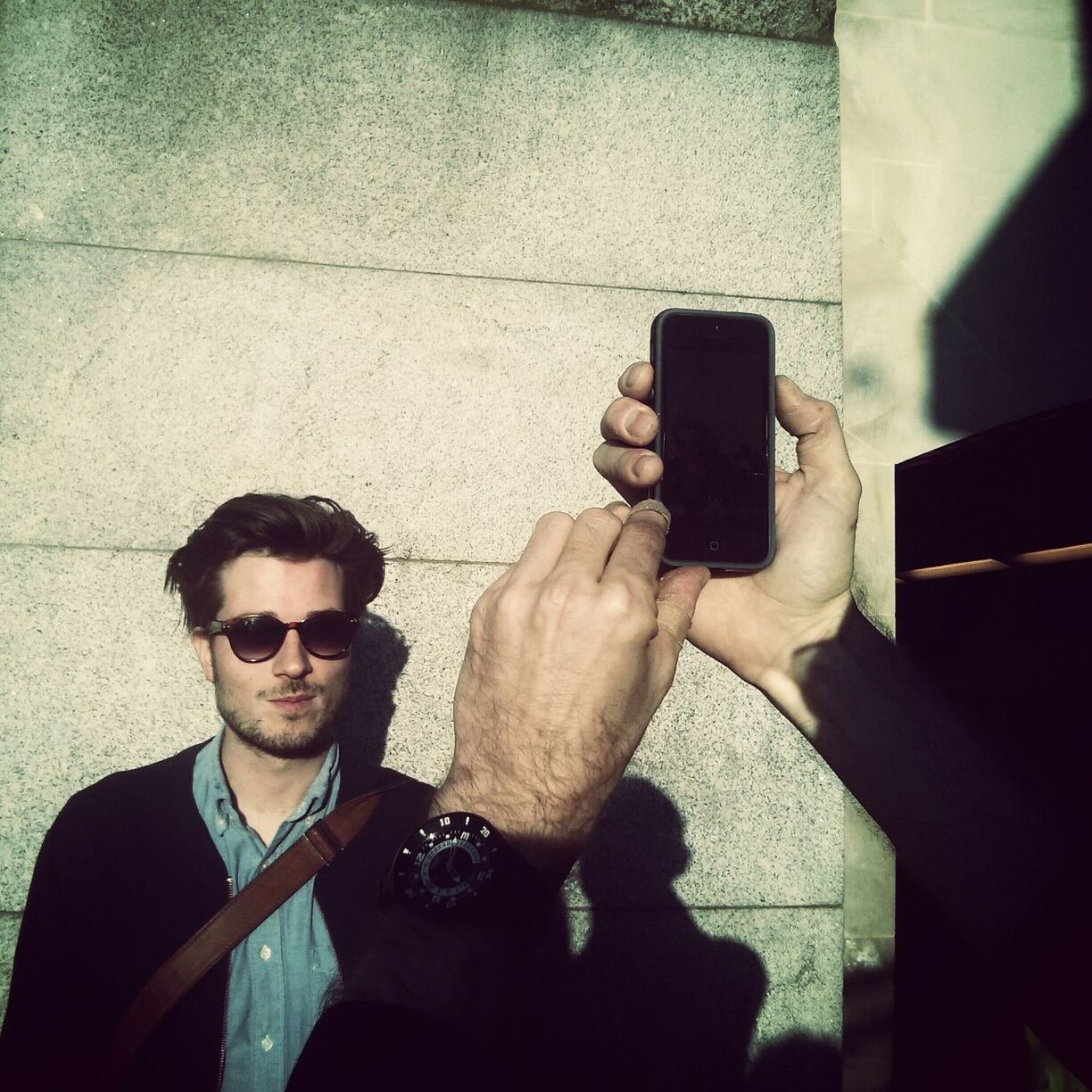 Hand photographing young man against the wall