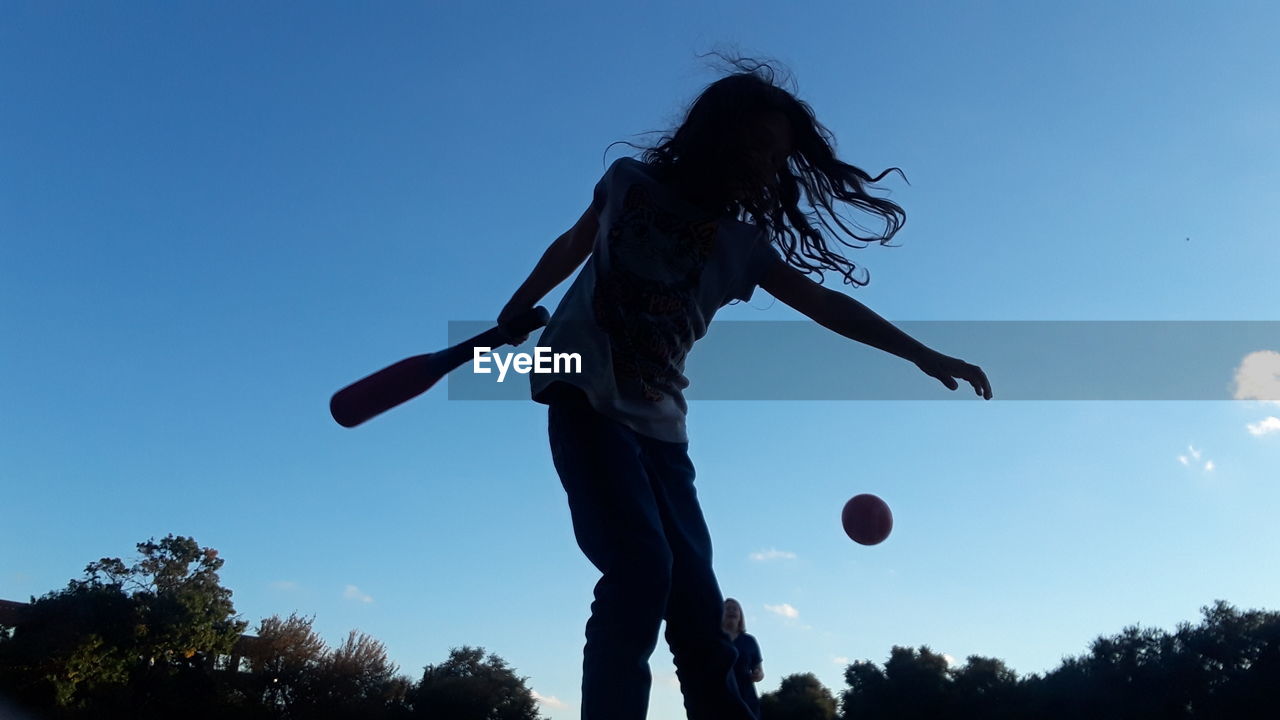 Low angle view of people playing against blue sky