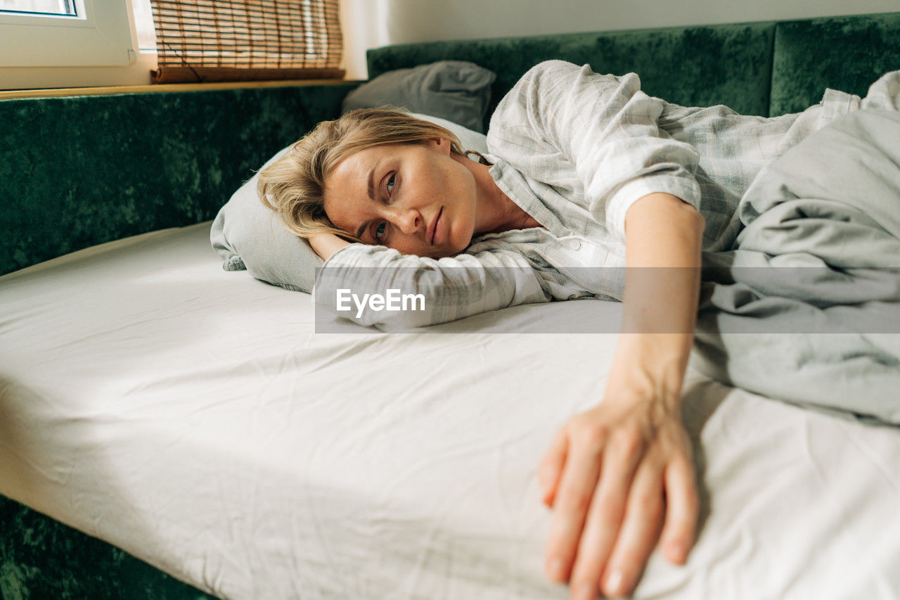 Beautiful blonde woman in pajamas on the bed in the morning after waking up.